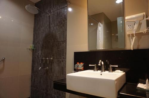 雅加达珊迪卡卡拉巴加丁酒店的浴室配有盥洗盆和带镜子的淋浴