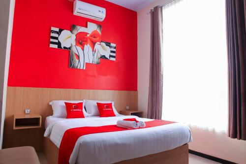玛琅D'SHARIO Hotel Kepanjen的红色的房间,设有一张红色墙壁的床