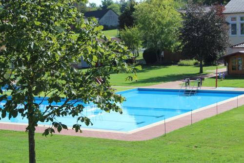 OttrauSonnenhof Ottrau的一座大游泳池,位于一个有树的院子内