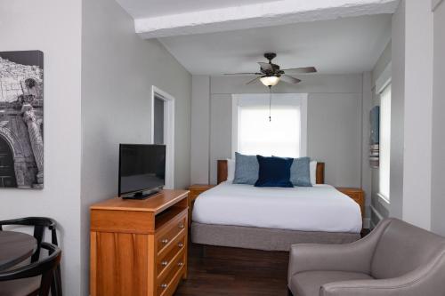 圣安东尼奥Club Wyndham Riverside Suites的一间卧室配有一张床、一台电视和一把椅子
