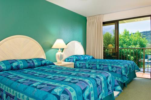利胡埃Kauai Beach Villas的带阳台的客房内的两张床