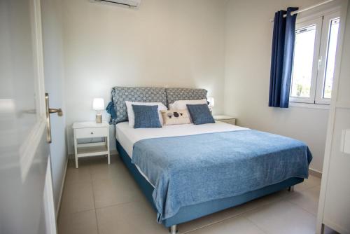 MetaxátaXarafailte Summer House的一间卧室配有一张带蓝色床单的床和一扇窗户。