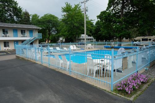 威斯康星戴尔星光汽车旅馆的游泳池周围的蓝色围栏,带白色椅子