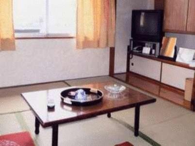 广岛天龙日式旅馆的客厅配有咖啡桌和电视