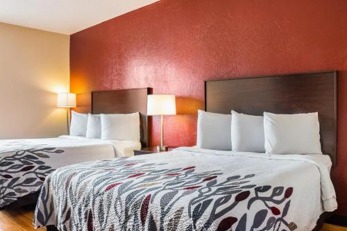 杜马Red Roof Inn Dumas的红色墙壁的酒店客房内的两张床