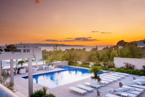 马卡尔斯卡Poseidon Mobile Home Resort的一个带躺椅的游泳池,享有日落美景
