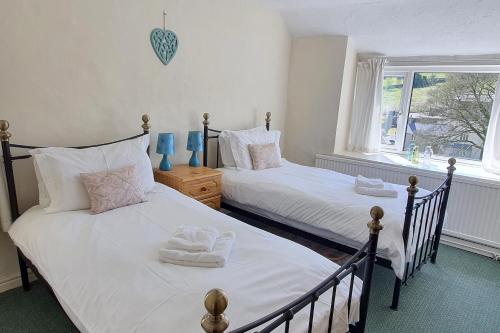 泰德斯韦尔Cornerstones Cottage, Tideswell的带窗户的客房内设有两张单人床。