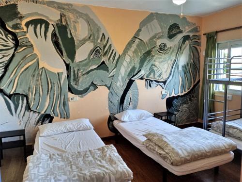 穆尔西亚拉卡萨福尔德旅舍的一间设有两张床的客房,墙上挂着壁画