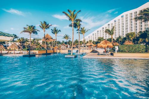 坎昆Iberostar Selection Cancun的棕榈树度假村的游泳池以及大楼