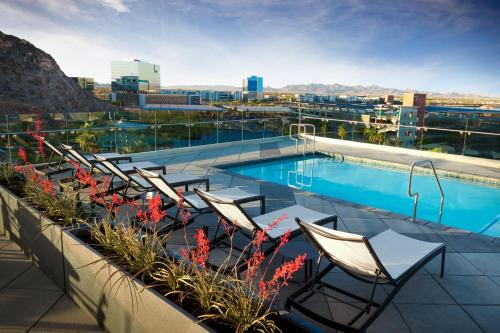 坦培Hyatt House Tempe Phoenix University的一座带椅子和鲜花的建筑屋顶上的游泳池