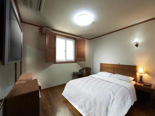 首尔豪门酒店的卧室设有一张白色大床和一扇窗户。