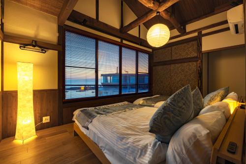 叶山町StellaStoria HAYAMA Seaside house with open-air bath的一间卧室设有一张大床和一个大窗户