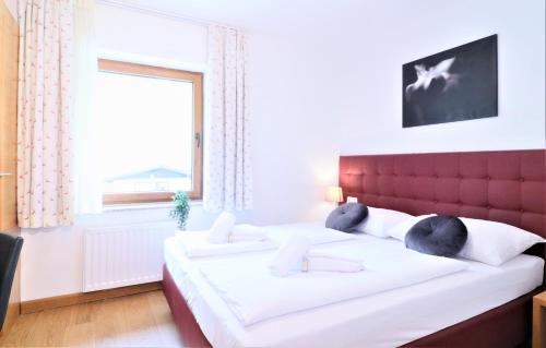 滨湖采尔Chalet Schmittenbach - Pinzgau Holidays的一间卧室配有一张带红色床头板的床和窗户