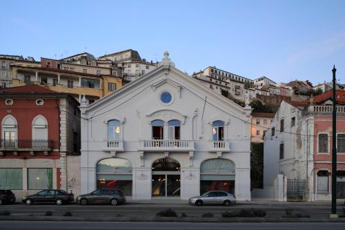 科英布拉Zero Box Lodge Coimbra的一座白色的建筑,前面有汽车停放