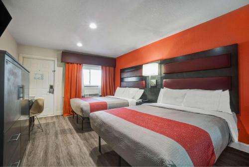 BellvilleMotel 6 Bellville, OH的酒店客房设有两张床和橙色的墙壁。