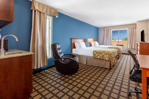 罗切斯特Baymont by Wyndham Rochester Mayo Clinic Area的配有一张床和一把椅子的酒店客房