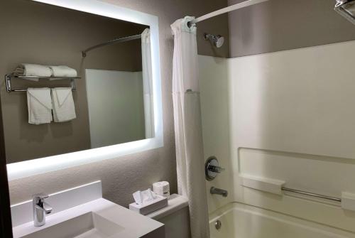 格里利格里利速8酒店的浴室配有盥洗盆、镜子和浴缸