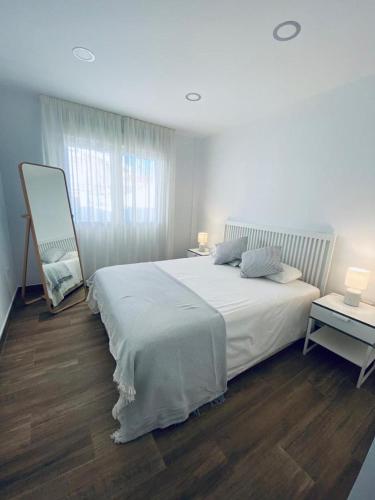 阿尔姆尼卡PRECIOSO APARTAMENTO EN EL TESORILLO的白色卧室配有一张大床和一张桌子