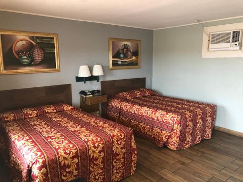 金斯维尔Budget inn的酒店客房设有两张床,墙上挂有绘画作品