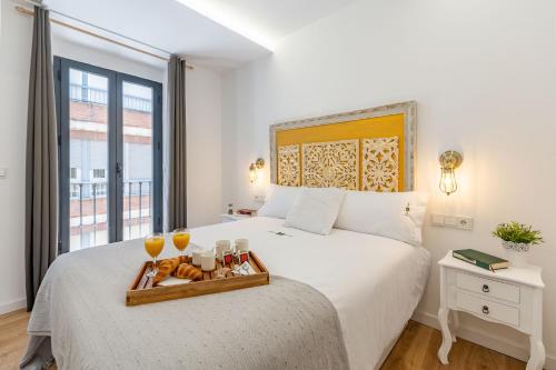 格拉纳达Granaxperience Apartamentos La Maleta的一间卧室配有一张床,上面放着一个食物托盘