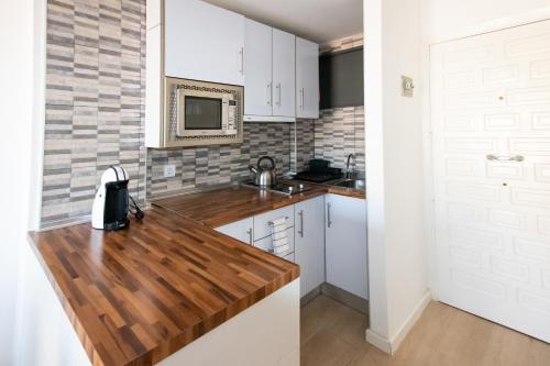 贝纳尔马德纳Dream Studio in Benalmadena Costa del Sol的厨房配有白色橱柜和木制台面