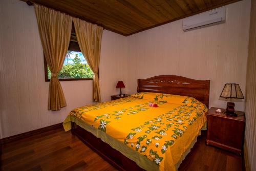 Maharepa莫雷阿高尔夫汽车旅馆的一间卧室配有一张带黄色棉被的床和窗户