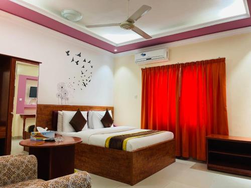 拉斯阿尔卡麦Al Nakheel Hotel Apartments的一间卧室配有床和红色窗帘