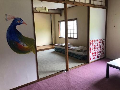 富山白色奇迹旅馆的一间设有镜子的客房,墙上挂着孔雀画