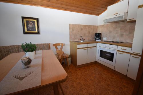 比希尔巴赫Landhaus Bichlbach的厨房配有白色橱柜和木桌