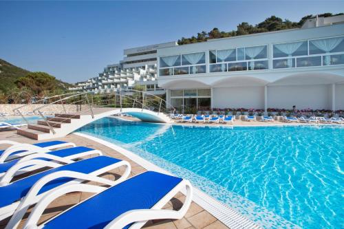 拉巴克纳西斯酒店 - 玛斯林尼卡酒店及度假村的一座带蓝白色椅子的游泳池和一座建筑