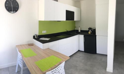 卡西斯Cassis Lodges的厨房配有白色橱柜和一张带绿色墙壁的桌子