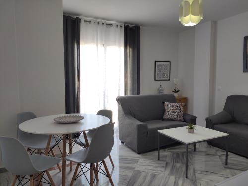 马拉加Apartamentos Málaga junto al Centro的客厅配有沙发和桌椅