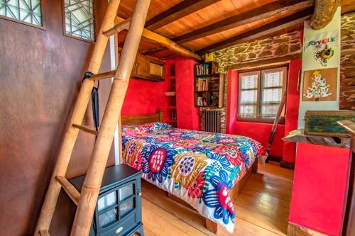 FrejulfeLa Casa de la Naturaleza的卧室设有红色的墙壁、一张床和梯子