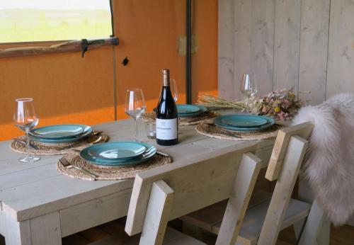 蒂尔堡Luxe safaritenten Petit013 - nieuw的一张带盘子的桌子和一瓶葡萄酒