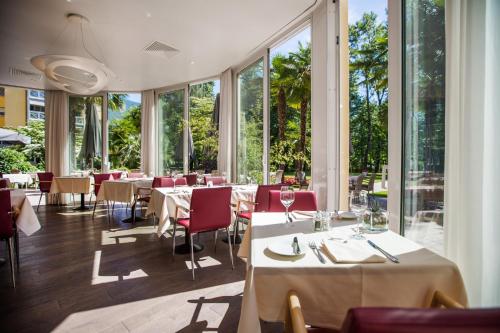 洛迦诺Tertianum Residenza Al Lido - Appartements & Restaurant的餐厅设有桌椅和大窗户。
