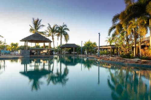 ExmouthNingaloo Caravan and Holiday Resort的棕榈树和建筑的海水游泳池