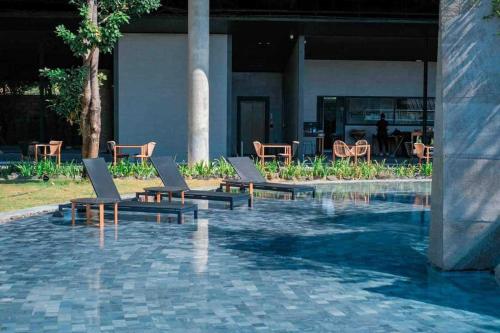 碧差汶Livist Resort phetchabun的一座带躺椅和桌子的游泳池以及一座建筑