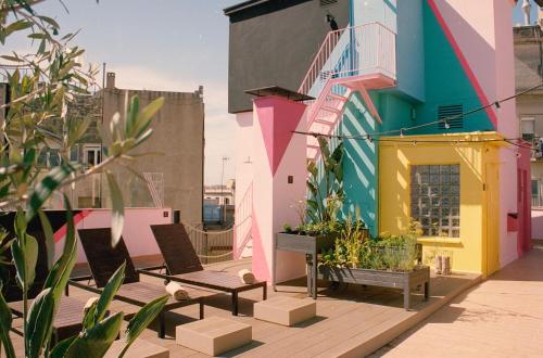 巴塞罗那波尔与格蕾丝酒店的阳台配有两把椅子,酒店大楼色彩缤纷。