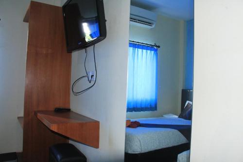 库塔Asher Bali Transit的一间设有床铺和墙上电视的房间