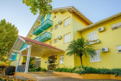 新彼得罗波利斯普萨达达内维酒店的黄色的房子,设有蓝色的阳台和棕榈树