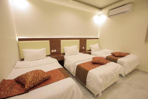 Al Qubsahمنتجع جزيرة الروز بالهدا的一间设有三张床和棕色枕头的房间