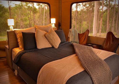 Boonah克车河边豪华帐篷的卧室配有带枕头的床铺和窗户。