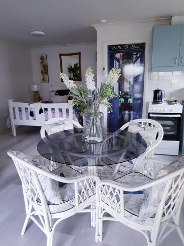 海伊Black Sheep Cottage Hay的一张带白色椅子和花瓶的玻璃桌