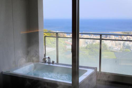 热海阿塔米弗加酒店的大窗户前的浴缸