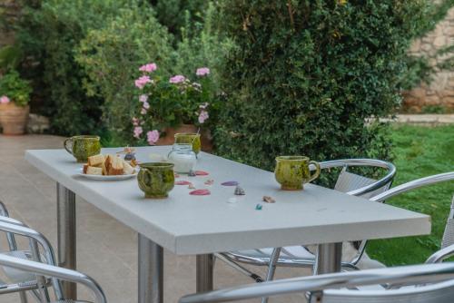 卡拉马基Arsinoi Studios and Apartments的一张带两个杯子的白色桌子和一盘食物