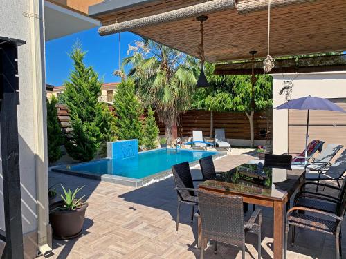帕福斯Shanti Paphos Villa的一个带桌椅的庭院和一个游泳池