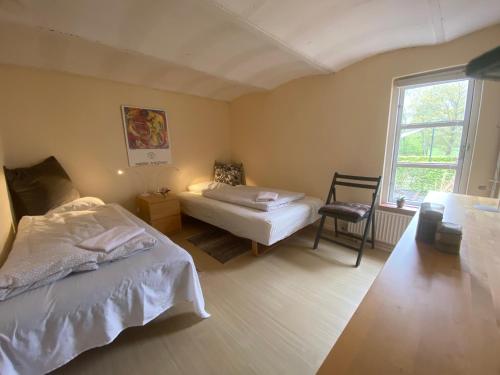 FarsøMargretelyst Ferielejlighed的一间卧室设有两张床、一把椅子和一个窗户。
