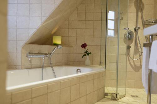 凯图姆Ferienhaus Honigklee im Lüüvhoog的浴室配有浴缸和带花卉的淋浴