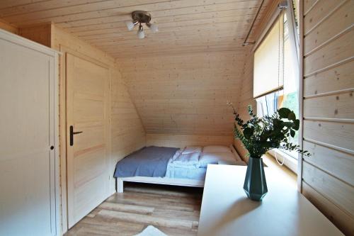 帕瑟姆Sosnowe Wzgórze的一间小卧室,配有一张位于木制房间内的床
