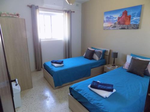 圣保罗湾城Sunshine Holiday Apartment 5 with Spectacular Seaviews的一间卧室设有两张带蓝色床单的床和窗户。